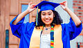a young woman proudly wearaing a blue graduation cap and gown